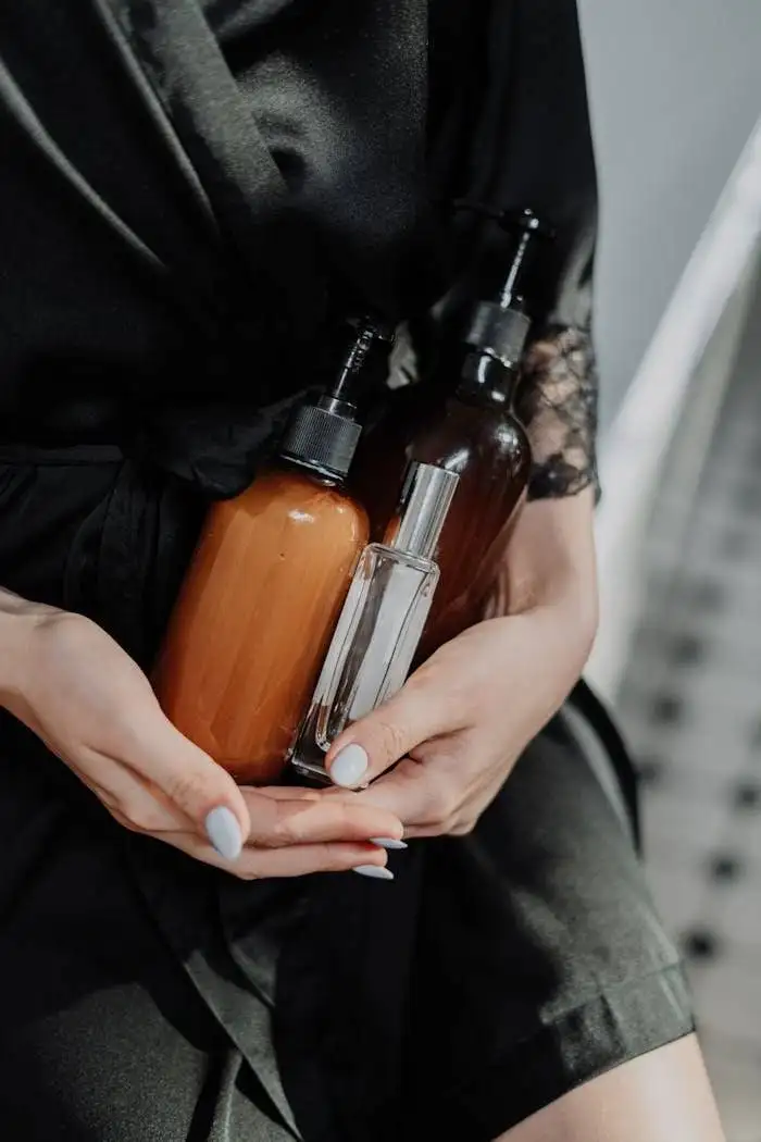 A woman in a black silk robe holds eco-friendly cosmetic bottles, highlighting zero waste lifestyle.
